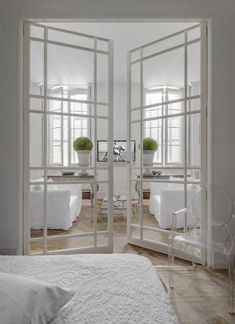 a bedroom with white walls and flooring has large mirrors on the wall to make it look like they are in an open airy space