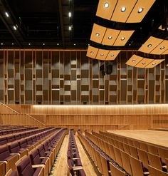 an empty auditorium with rows of seats and wood paneling on the walls, along with lights overhead