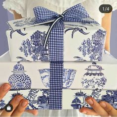 two hands holding blue and white boxes wrapped in ribbon, with the lid pulled down