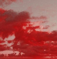 an airplane is flying in the sky with red clouds above it and another plane on the ground