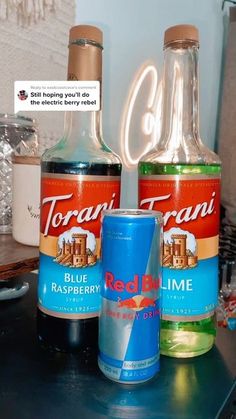 two bottles of red bull and blue raspberry are sitting on a counter top