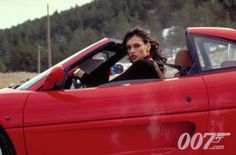 a woman sitting in the driver's seat of a red sports car