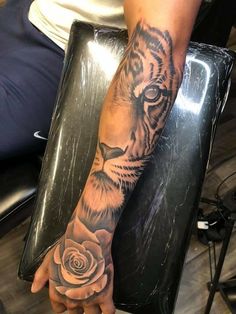 a person with a tiger tattoo on their arm holding a rose in the other hand