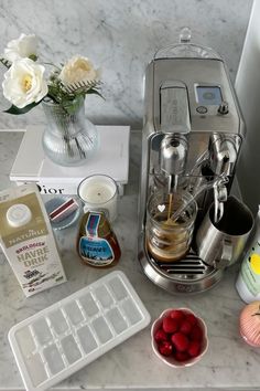 the coffee maker is sitting on the counter next to some other items that include raspberries