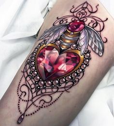 a woman's thigh with a heart and wings tattoo on her leg, decorated with jewels