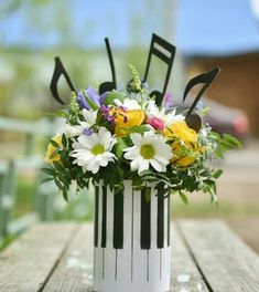 an arrangement of flowers in a white vase on a wooden table with black and white stripes