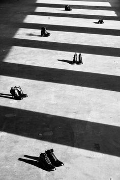 black and white photograph of people's shoes laying on the ground with long shadows