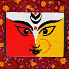 an art work with two faces painted on red and yellow paper, surrounded by flowers