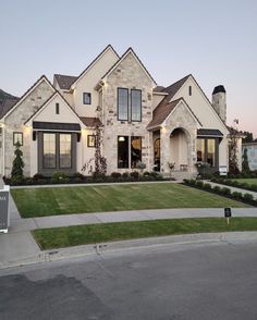 a large house with lots of windows and grass in front of the driveway, along with a mailbox