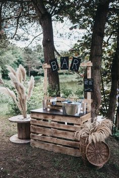 an outdoor bar made out of pallets and wooden crates is set up in the woods