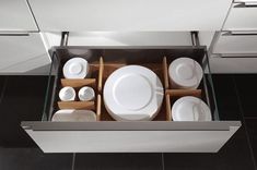 an open drawer with plates and cups in it