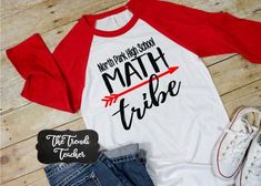 a red and white shirt with the words math tribe next to it on a wooden floor