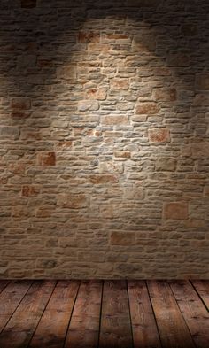 an empty room with brick wall and wood flooring, illuminated by a spot light