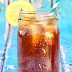 a mason jar filled with liquid and lemon wedged into the top, sitting on a blue wooden table