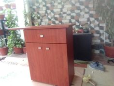 a wooden cabinet sitting on top of a floor next to a potted planter