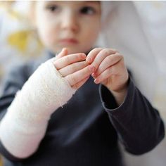 a little boy with a cast on his arm and hand in the other hand, sitting down