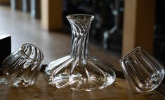 three glass vases sitting on top of a wooden table next to a black box