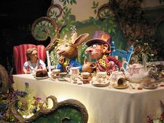 the table is covered with figurines and teacups, including two rabbits