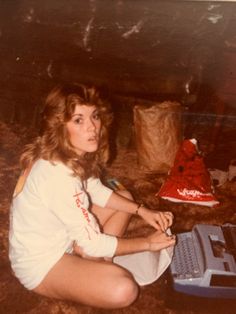 a woman sitting on the ground with a laptop computer in front of her and an object behind her