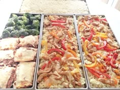 four trays filled with different types of food sitting on top of a white table