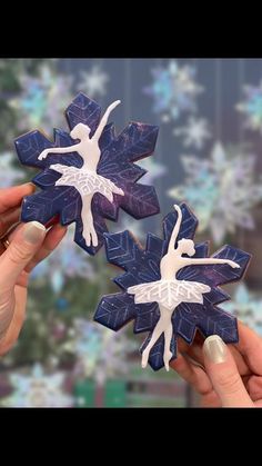 two blue and white snowflakes are being held by someone's hands