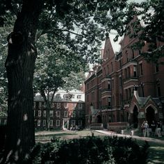 an old photo of people walking in front of a large brick building with many windows