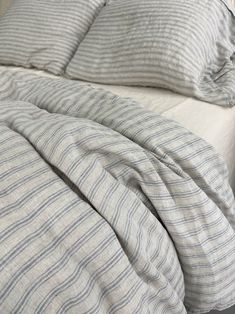 an unmade bed with blue and white striped sheets