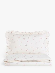 a white pillow with pink flowers and ruffles on the bottom, sitting next to a