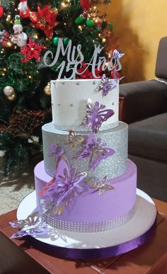 a three tiered cake sitting on top of a table next to a christmas tree