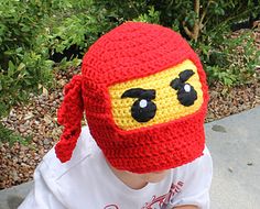 a small child wearing a red and yellow crocheted hat with eyes on it