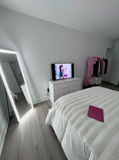 a bedroom with a bed, dresser and television on the wall in front of it