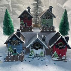 a group of small houses sitting in the snow with christmas decorations on top of them