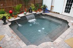 a small pool in the middle of a patio with a waterfall coming out of it