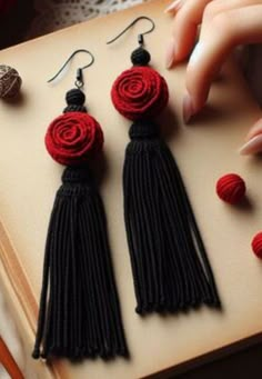 three pairs of black and red tasseled earrings on top of an open book