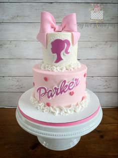 a pink and white cake with a bow on top