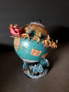 a small globe with animals on it and a santa clause sleigh in the middle