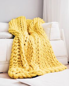 a large chunky yellow blanket sitting on top of a white couch