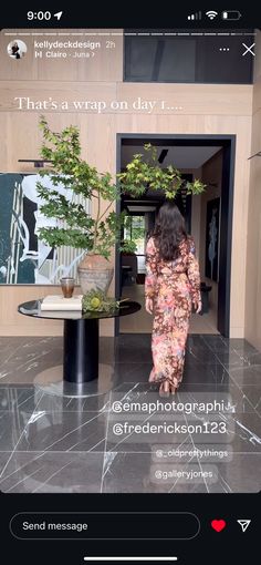 a woman walking into a building with a tree in the doorway and an advertisement on the door