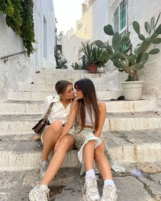 two young women sitting on steps kissing each other