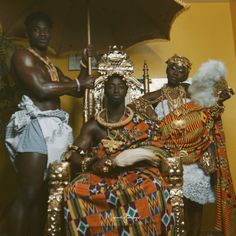 three black men dressed in african clothing and holding an umbrella