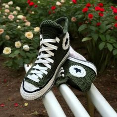 there is a pair of shoes that are on top of a white rail in front of some flowers