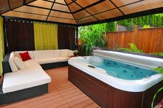 a large hot tub sitting on top of a wooden floor next to a white couch