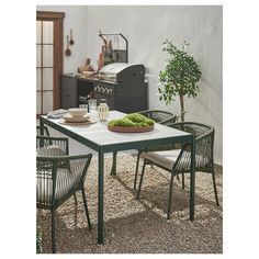 an outdoor dining table with four chairs and a potted plant