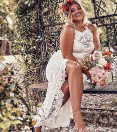 a woman sitting on a bench with flowers in her hair and wearing a white dress