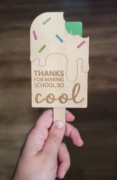 a hand holding up a wooden sign that says thanks for making school cool