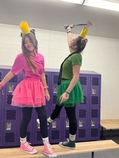 two girls in costumes are standing on a bench