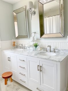 a white bathroom with two sinks and mirrors