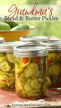 four jars filled with pickles sitting on top of a table