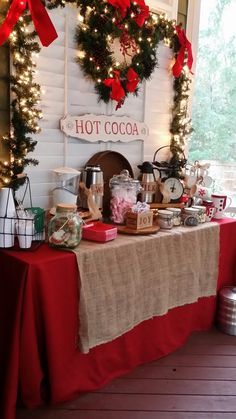 a table covered in red and white christmas decorations next to a fireplace with wreaths on it