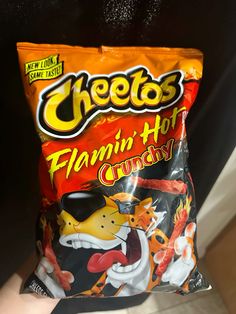 a hand holding a bag of cheetos flami hot crunchy chips in it's palm